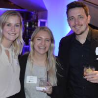 Three alumni pose for a photo
